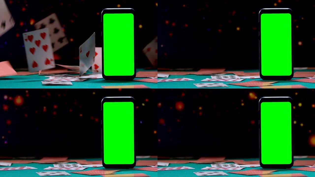 带有绿色屏幕的智能手机站在掉落的扑克牌的背景上
