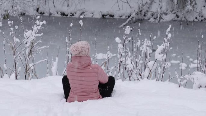 女人看着雪花落在白雪皑皑的森林里