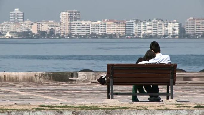 夫妇坐在长凳上看着大海