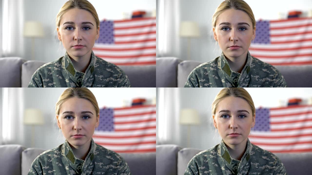 悲伤的女兵身穿迷彩服看着镜头，美国国旗的背景