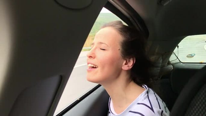 幸福-年轻的女人在汽车上，手在空中玩耍
