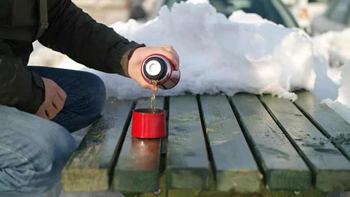 Man pours tea from a thermos winter