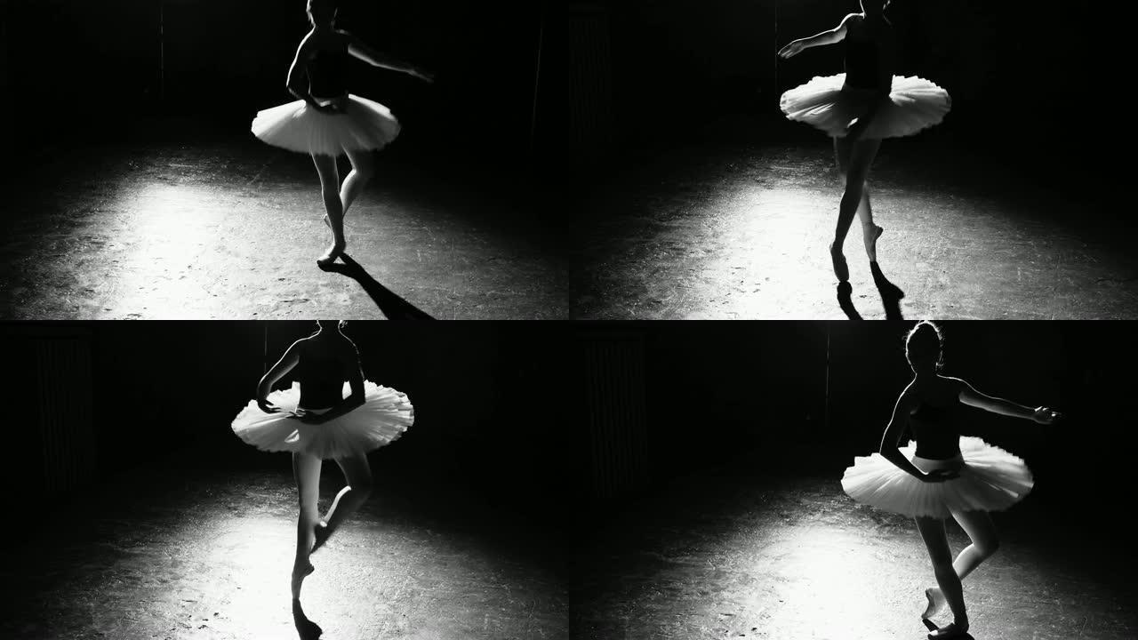 专业灵活的芭蕾舞演员在工作室的黑色背景下，在她的尖头芭蕾舞鞋上跳舞。女人穿着芭蕾舞短裙和尖头鞋展示经