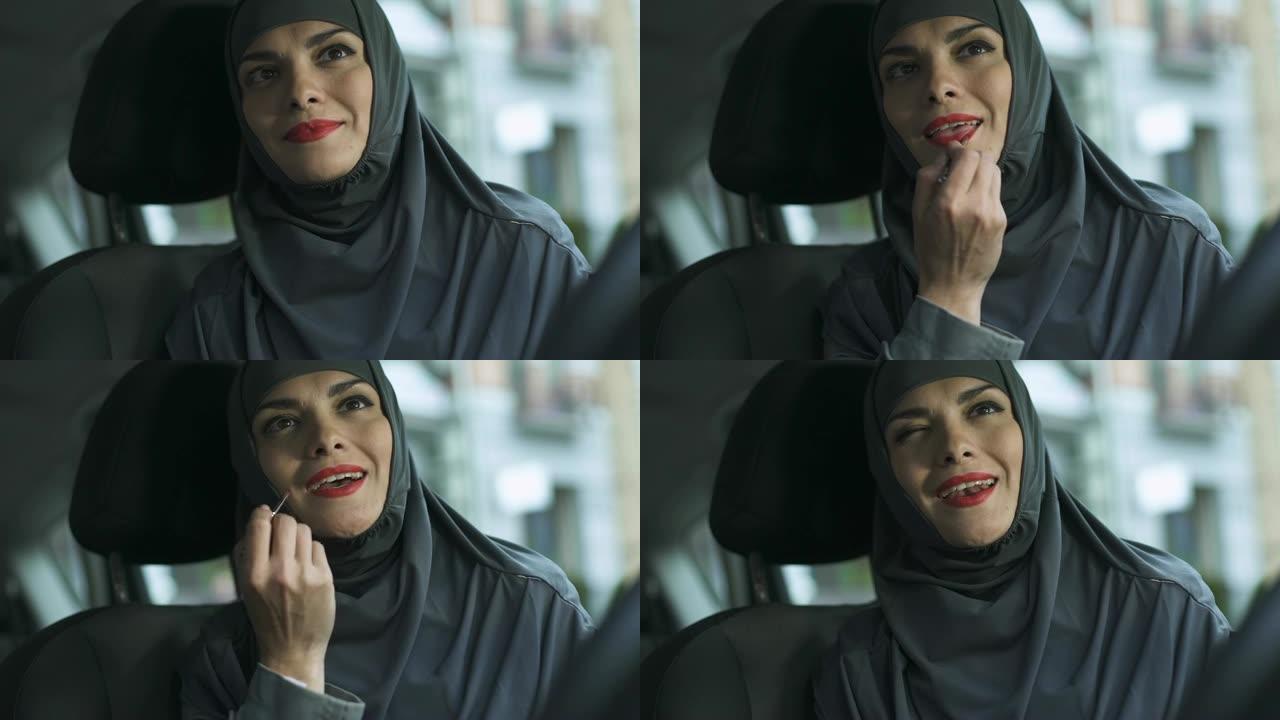 自信的阿拉伯女士在自动应用红色口红，调情眨眼