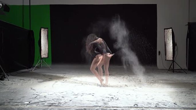 美丽的芭蕾舞演员在工作室里用粉雪在旋转木马里跳舞。慢动作