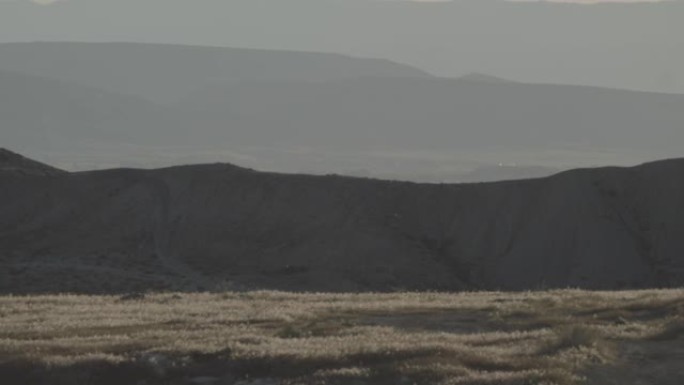 在科罗拉多州西部的草木，多山，高沙漠景观上吹着灰尘的风的平移镜头