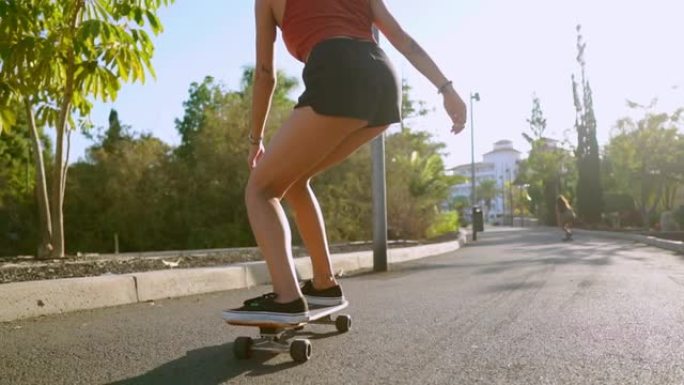 慢动作女孩在公园里用棕榈树骑滑板