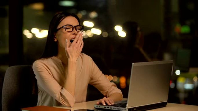 无聊的女人在笔记本电脑上工作，加班精疲力尽，缺乏动力