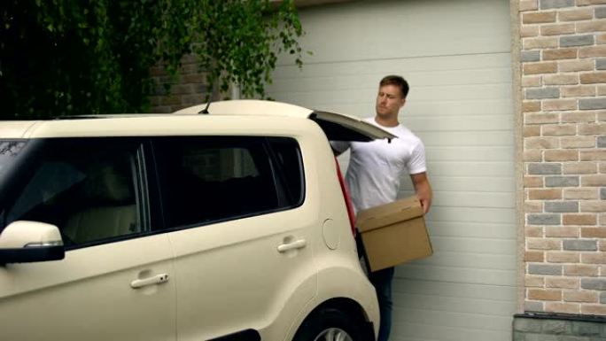 休闲男性把纸箱放在车里，搬进新房子，房地产