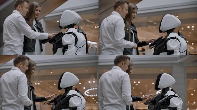 商场里的一男一女通过点击屏幕和微笑与机器人顾问互动。机器人机器人帮助人们。