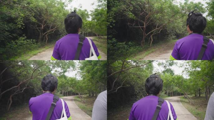 在裸露的森林中行走的topknot头发的泰国男子