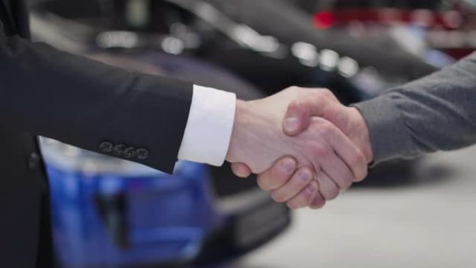 男性高加索人的特写镜头给顾客提供车钥匙并握手。经销商和客户就汽车购买达成协议。汽车经销商，汽车工业。