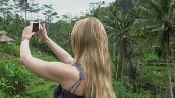 年轻的旅游女子在印度尼西亚巴厘岛的稻米区拍照