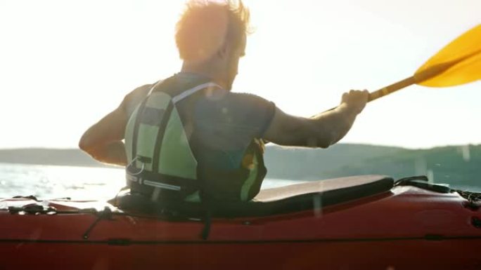 SLO MO TS男子在阳光下在海上划独木舟
