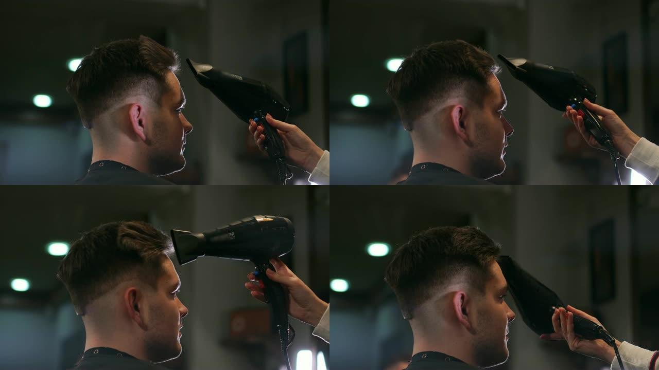 沙龙中的男性发型。理发店的男人吹风。理发师用吹风机定型头发。完成美发。理发店的吹风机男