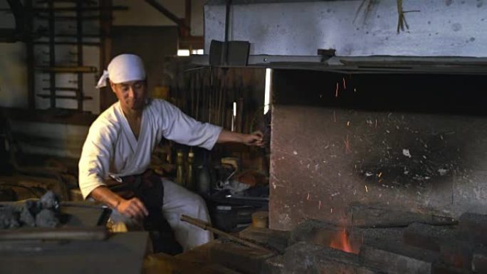 铁匠在炉子上加煤手工做武器制作刀剑