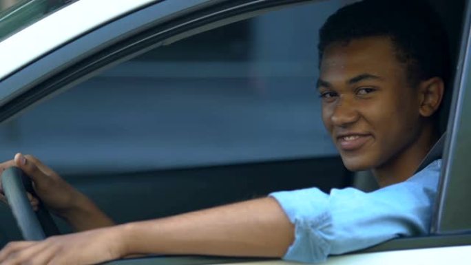 非裔美国少年男孩在汽车上竖起大拇指，获得驾驶执照