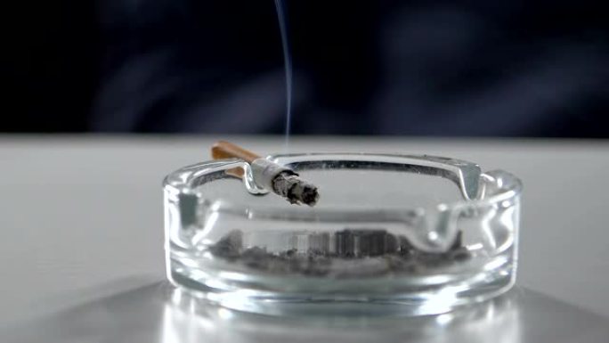 烟雾滴落，香烟在烟灰缸上慢慢闷烧，有着火的危险