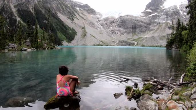 年轻女孩在寒冷、清澈的山湖中涉足脚趾