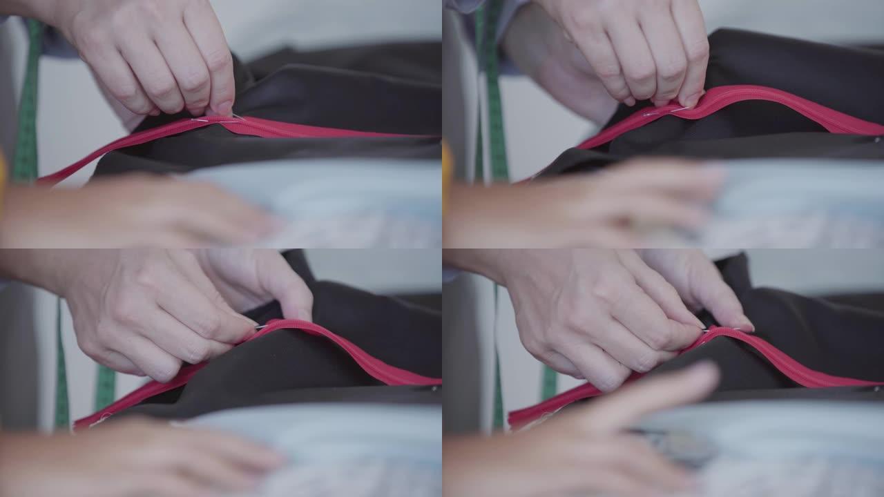 女裁缝的特写手在缝制前用别针将拉链固定在织物上。
