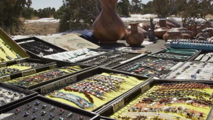 多莉拍摄的美国原住民风格的珠宝和陶器在户外展示，以便在冬季的犹他州阳光明媚的日子购买