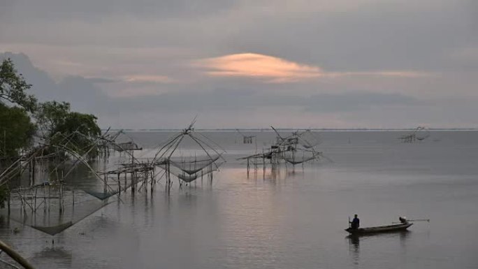 泰国Phatthalung的Park Pra村，宋卡湖的日出，有手工制作的钓鱼陷阱，湖中有一艘木头船