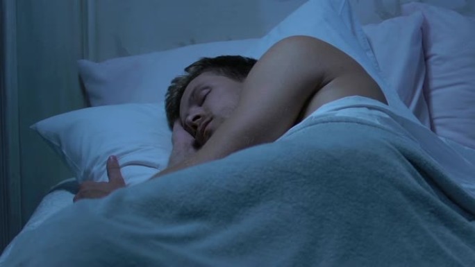 男人安静地睡在干净新鲜的床上，良好的睡眠条件，正位