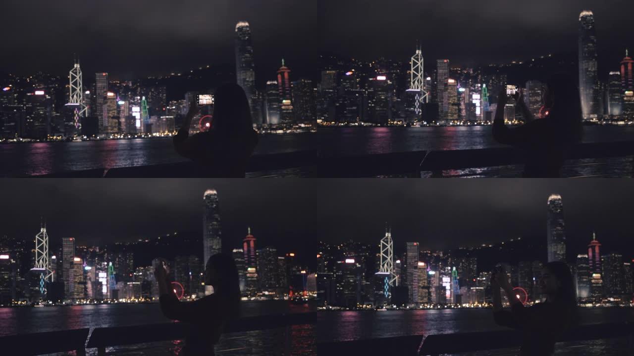 旅行者们用手机拍摄香港的夜景。
