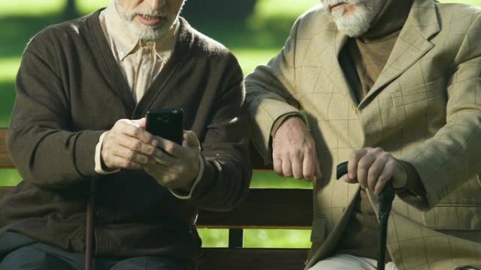 老人用手杖向朋友展示智能手机照片，现代技术