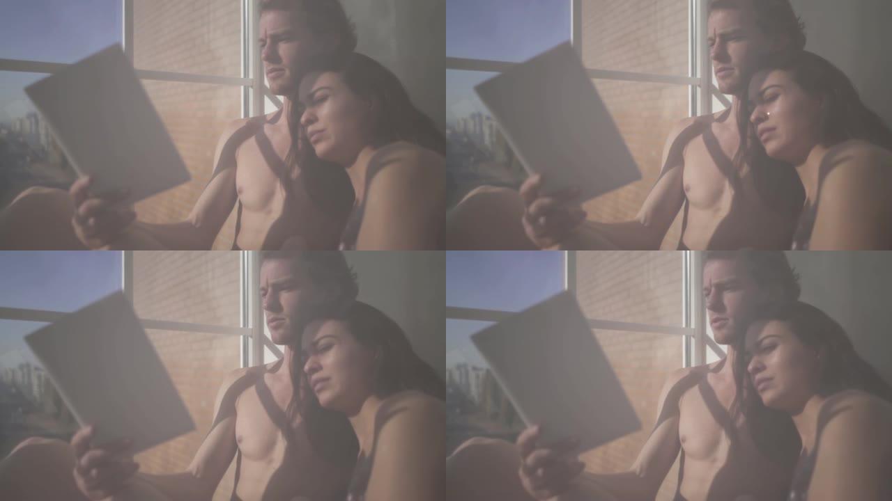 美丽性感的裸体女人和年轻的裸体金发男人躺在一起，她透过薄纱在窗户附近看书。女性脸上流着眼泪。