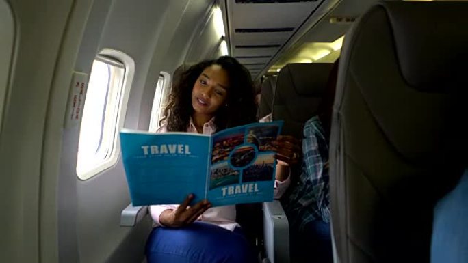 美丽的黑人妇女在空中飞行中微笑着看着旅行指南