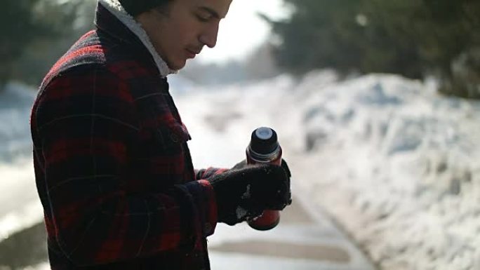 Man pours tea from a thermos winter