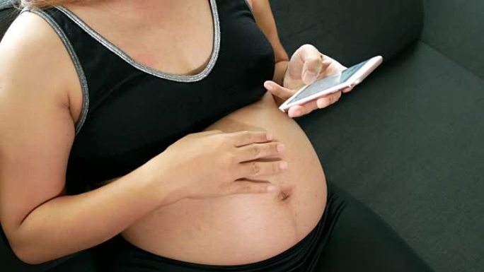 孕妇玩手机的镜头孕妇抚摸肚子胎儿安抚孕妇