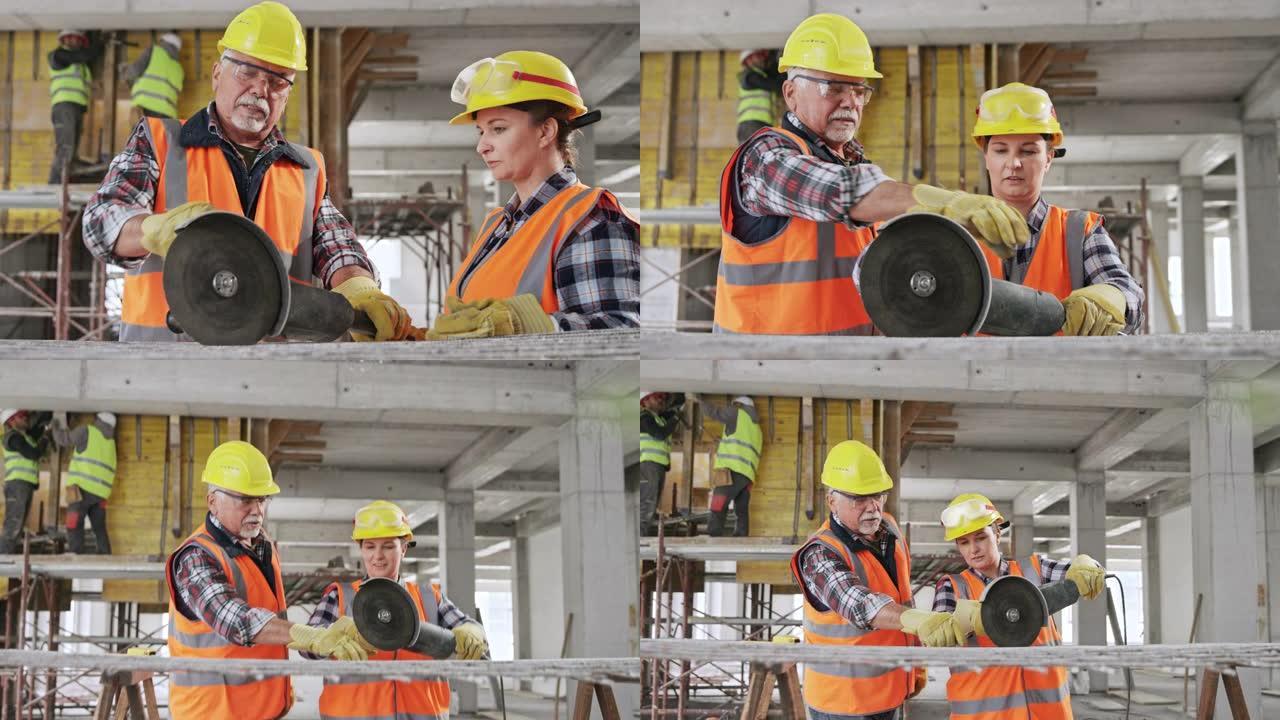 高级男性建筑工人展示女学徒如何握住大型角磨机切穿钢网