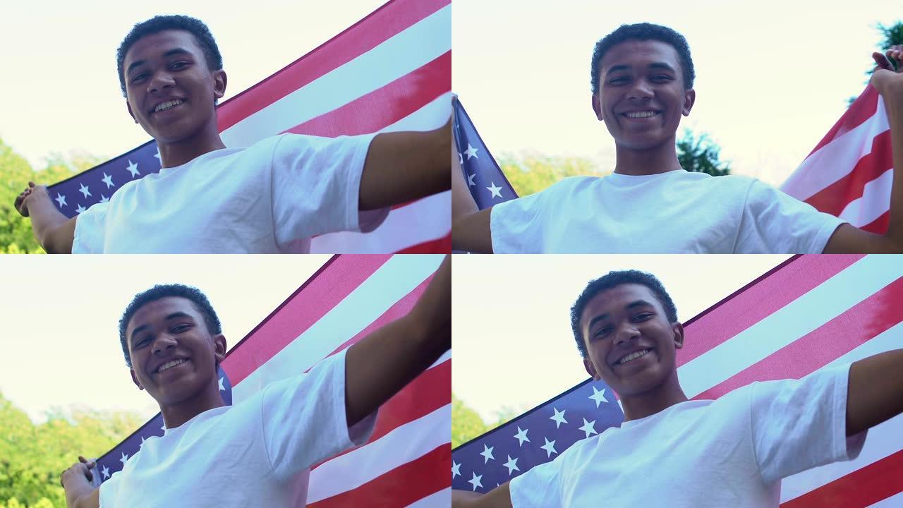 美国独立日，美国国旗在户外的镜头前微笑的美国黑人少年男孩