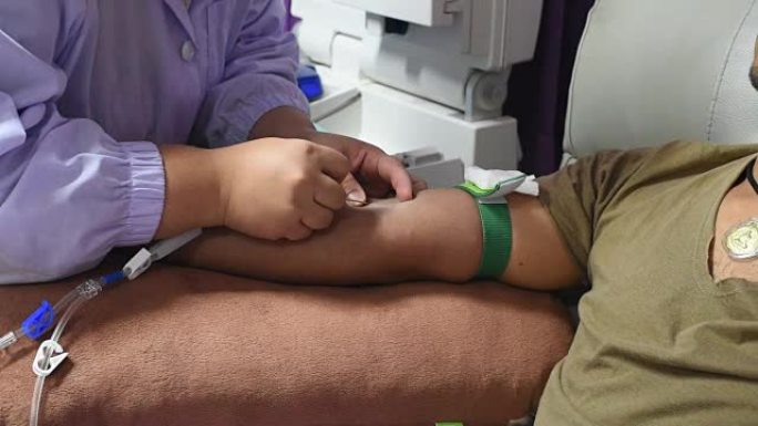 年轻的献血者为单个献血者血小板提供血液，护士在献血者静脉中刺针，