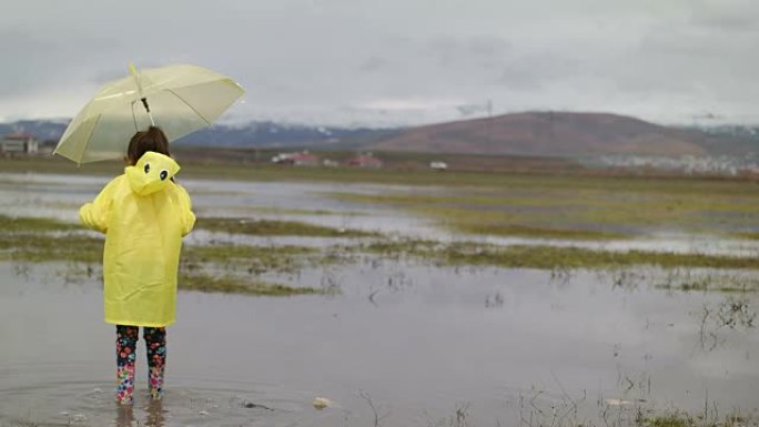 雨中的小女孩儿童戏水踩水雨伞雨衣