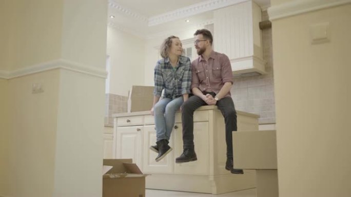肖像幸福的年轻夫妇坐在新公寓的厨房桌子上，讨论房子的布局。