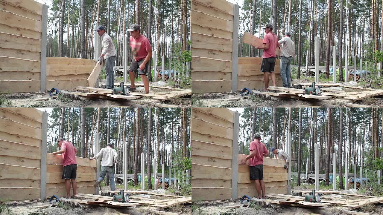 工人做木栅栏。造木屋木围墙树林小屋