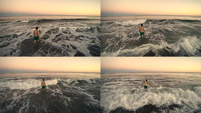 纽约州长岛日落时分，年轻人走进水中游泳的低空航拍画面。