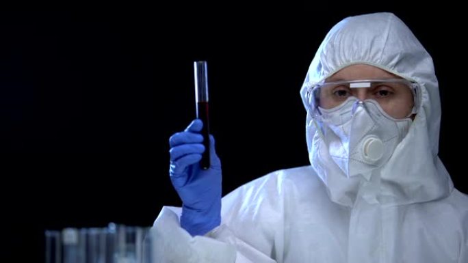 防护服中的女研究员检查试管中的油液，毒药