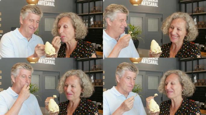 甜蜜的高级夫妇在谈话时在冰淇淋店分享冰淇淋