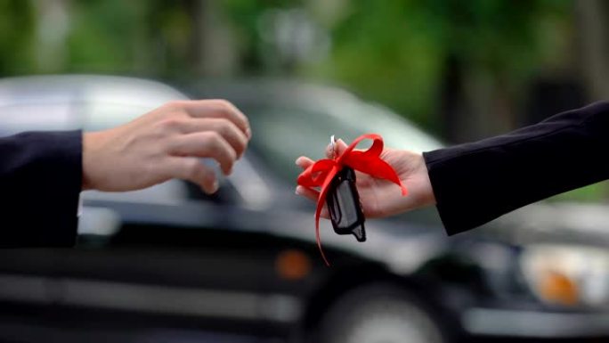 男人把带着大红色蝴蝶结的车钥匙送给女人，令人惊奇的惊喜，珍贵的礼物