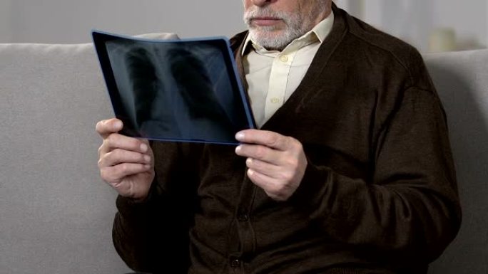 康复中的老年男性看着肺部x射线，对不治之症，健康感到不安