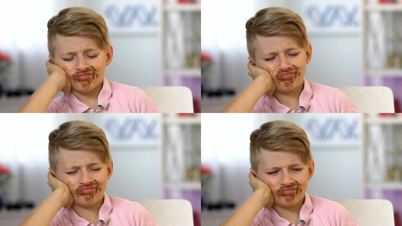 男孩牙痛，脸上沾满巧克力，孩子暴饮暴食