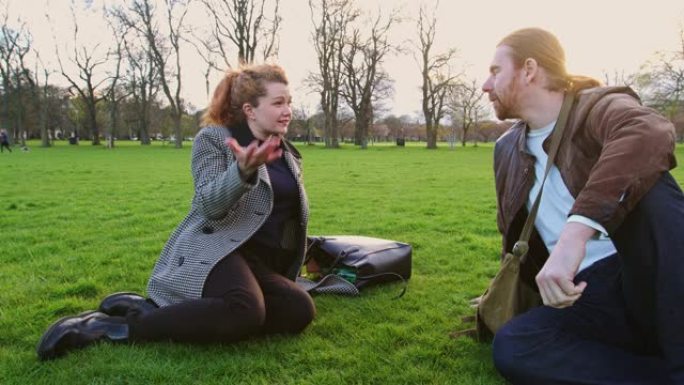 坐在爱丁堡公园草地上的聊天夫妇