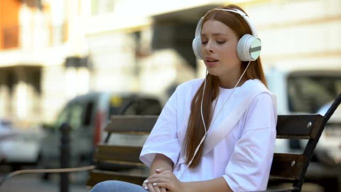 情绪悲伤的少女在耳机听抒情歌户外音乐应用程序