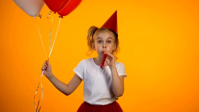 可爱的女孩拿着气球和派对吹风机庆祝生日，快乐
