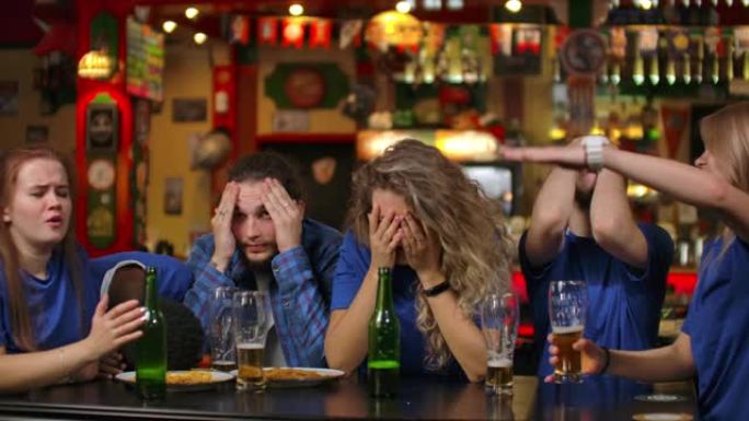 一群年轻人在酒吧里观看电视转播的体育赛事，情绪激动地等待着决定性的时刻，因为输掉了一支球队而感到悲伤