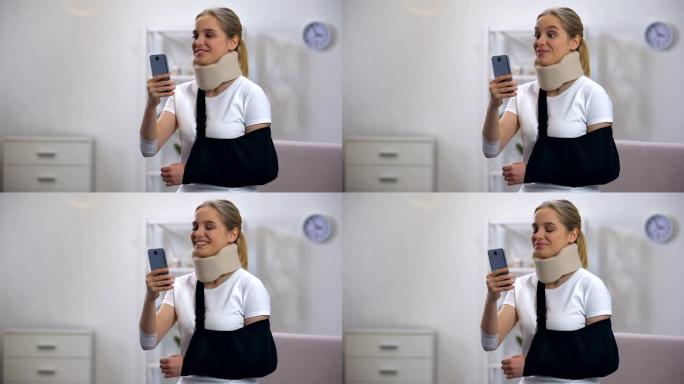 快乐的女人穿着泡沫颈圈和手臂吊带在手机康复中心聊天